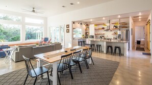 Une cuisine spacieuse dotée d’un îlot central, de tabourets de bar et d’un coin repas avec une grande table.