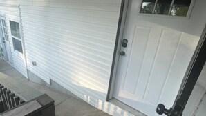 Una puerta de garaje blanca con una pequeña ventana, un timbre y un felpudo.