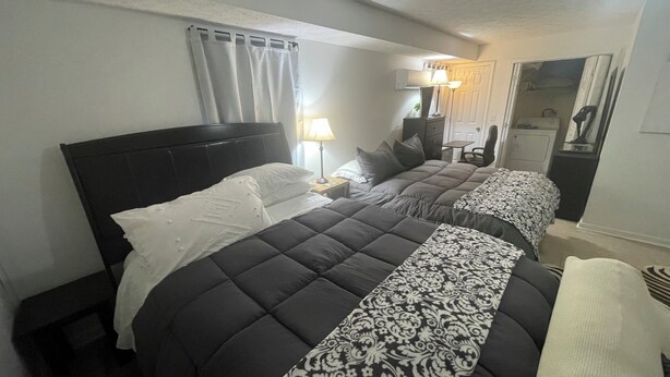 Habitación de hotel con dos camas, una mesita de noche, una lámpara, un aparador y un espejo.