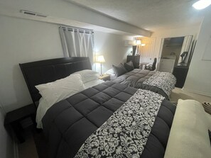 Una camera d'albergo con due letti, un comodino, una lampada, una cassettiera e uno specchio.