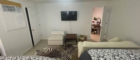 A bedroom with two beds, a TV, a desk, and a chair.
