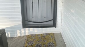 Una puerta blanca con una reja metálica negra y un pequeño ventanal encima.