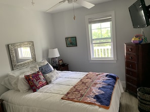 A bedroom with a bed, a dresser, a TV, a window, and a ceiling fan. - The Palms...A beautiful space in the perfect place. (Key West)