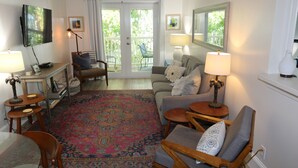 A living room with a television, a ceiling fan, a sofa, a coffee table, and a patterned rug. - The Palms...A beautiful space in the perfect place. (Key West)
