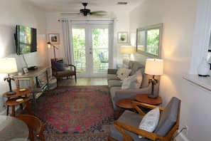 A living room with a television, a ceiling fan, a sofa, a coffee table, and a patterned rug. - The Palms...A beautiful space in the perfect place. (Key West)