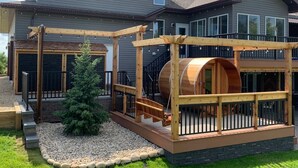 A two-story house with a deck, a wooden swing set, and a barrel-shaped structure. - Dragonfly Inn, Loft Suite with private entrance. (Sherwood Park)
