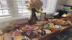A buffet table with various food items, a vase of flowers, and a sign that says "Let's EAT". - Dragonfly Inn, Loft Suite with private entrance. (Sherwood Park)