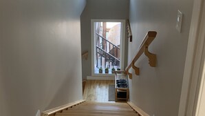 A staircase with wooden steps leading to a landing with a small window. - Dragonfly Inn, Loft Suite with private entrance. (Sherwood Park)