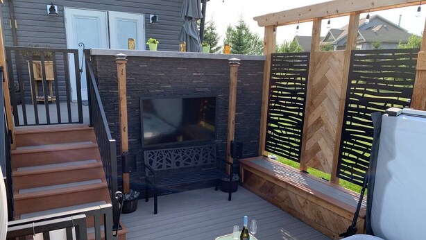 A deck with a hot tub, a fireplace, and a table with drinks. - Dragonfly Inn, Loft Suite with private entrance. (Sherwood Park)