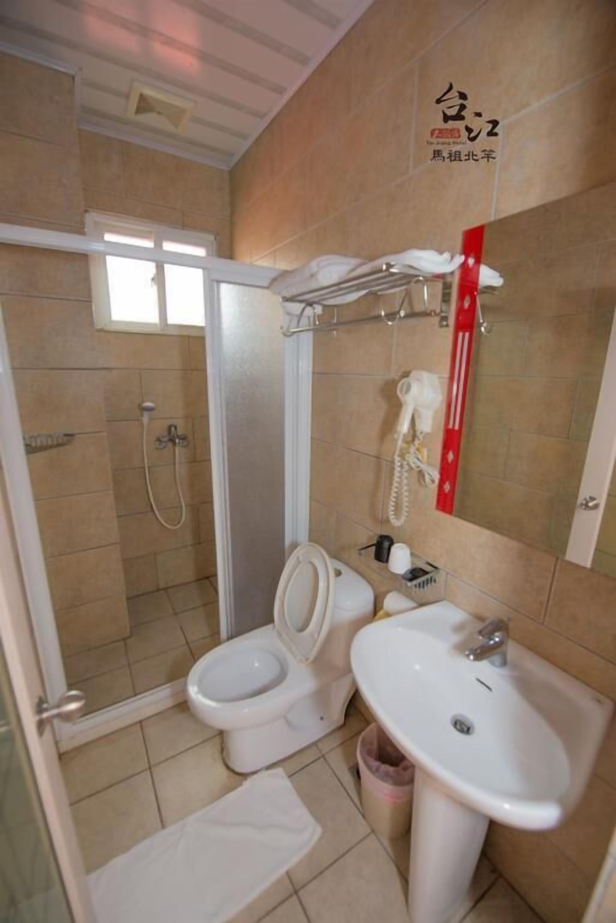 A bathroom with a toilet, sink, and shower.