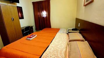 A hotel room with a bed, a desk, a chair, a wardrobe, and a television on the wall.