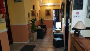 A hotel lobby with a tiled floor, a reception desk, a sofa, and a coffee table. - Hotel Paris (General San Martin)