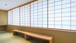 A room with tatami flooring, a low wooden bench, and a large shoji screen. - Hotel Muso (Kyoto)