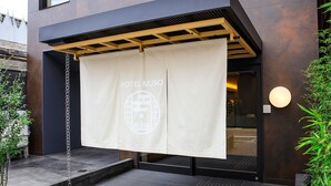A modern building entrance with a hanging banner displaying "HOTEL MUSO" and a globe logo. - Hotel Muso (Kyoto)