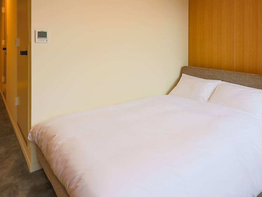 Ein Hotelzimmer mit einem Bett, einem Holz-Kopfteil, Teppichboden und einer Tür.