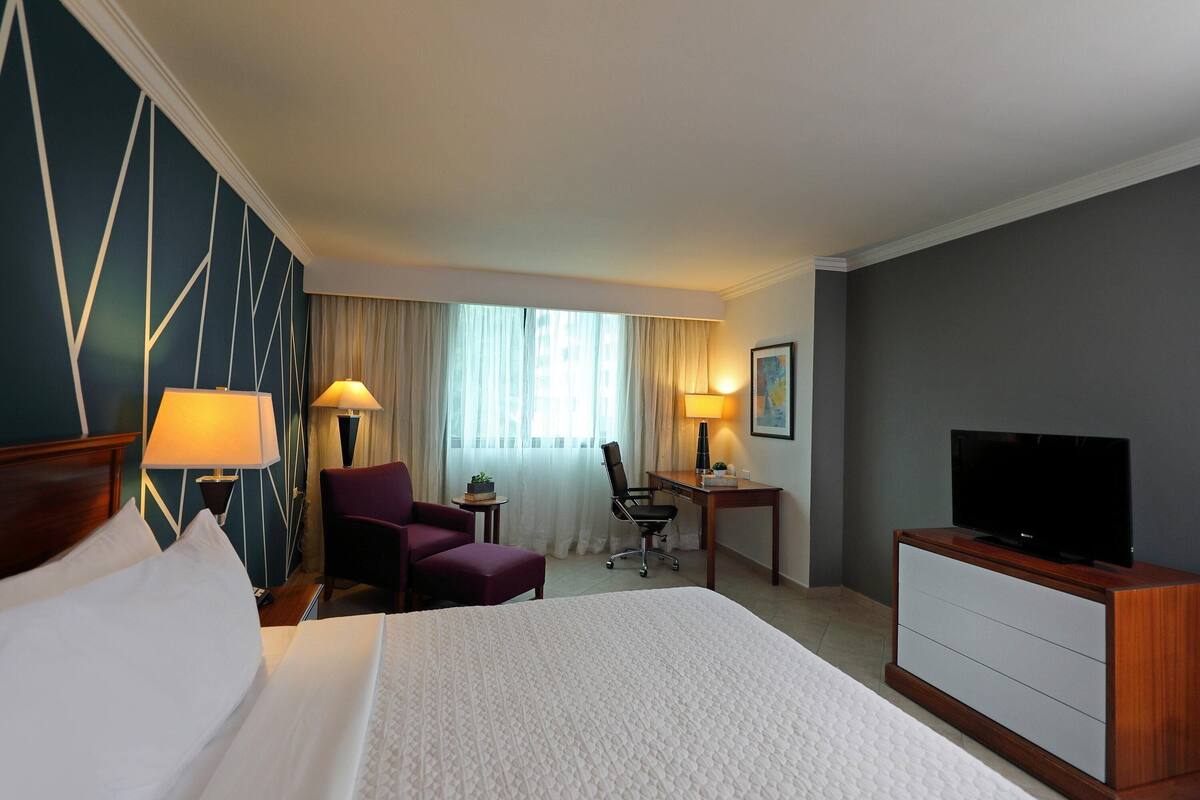Ein Hotelzimmer mit Bett, Schreibtisch, Stuhl, Fernseher und Lampe.