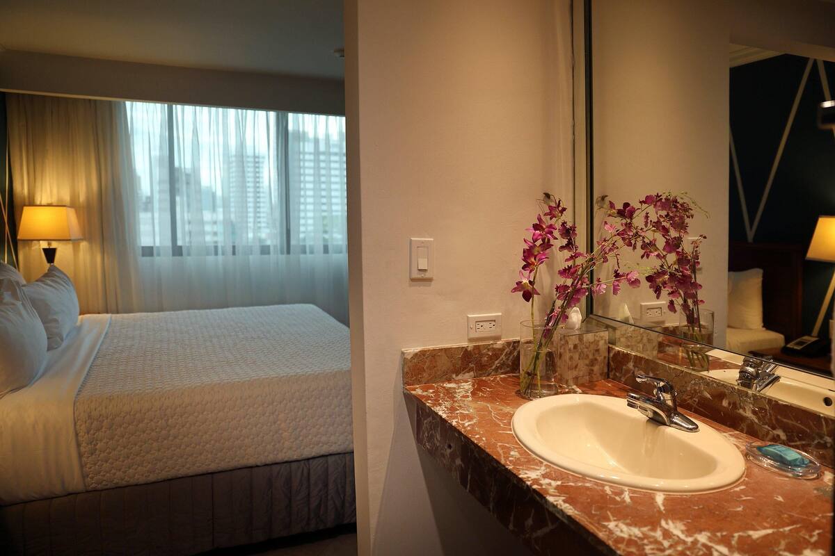 Ein Hotelzimmer mit einem Bett, einem Marmor-Waschtisch, einem Waschbecken und einem großen Spiegel.