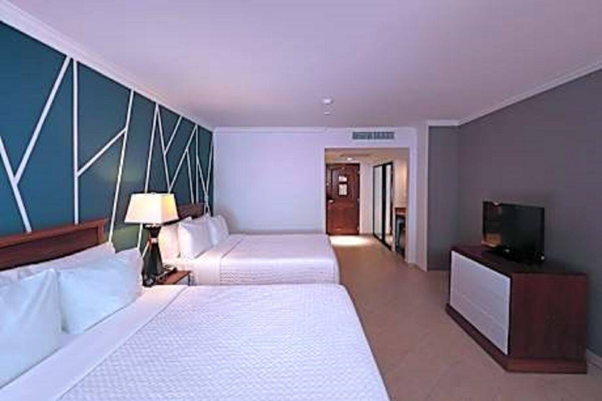 Ein Hotelzimmer mit zwei Betten, einem Fernseher und einem Schreibtisch.