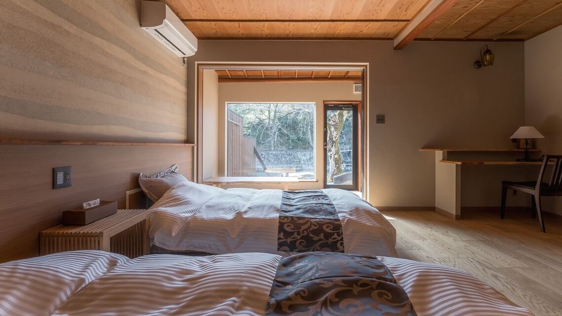 A bedroom with a large window, a desk, and a chair.
