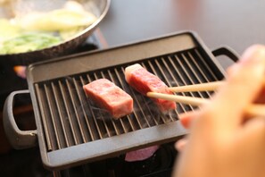 A grill with two pieces of meat being cooked. - OkutsuHotSpa Ikedaya Kajikaen (Kagamino)
