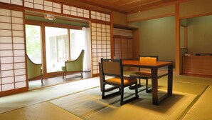 A traditional Japanese room with tatami flooring, a low table with chairs, and sliding doors. - OkutsuHotSpa Ikedaya Kajikaen (Kagamino)