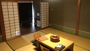 A traditional Japanese room with tatami flooring, a low table with a decorative item, and sliding doors. - OkutsuHotSpa Ikedaya Kajikaen (Kagamino)