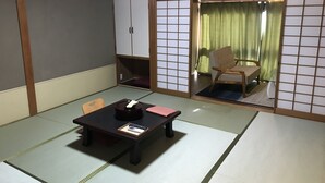 A traditional Japanese room with tatami flooring, a low table with a tea set, a wooden chair, and a sliding door leading to a balcony with a view of the outside. - OkutsuHotSpa Ikedaya Kajikaen (Kagamino)