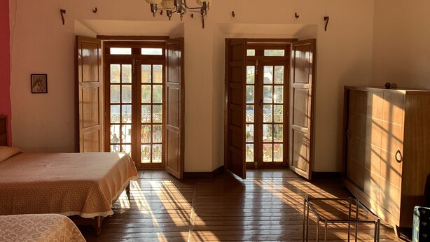 A room with wooden flooring, a bed, a wardrobe, and a chandelier.