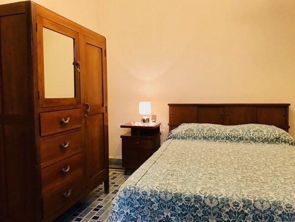 Une chambre à coucher avec une armoire en bois, une table de chevet avec une lampe et un lit avec une literie à motifs.