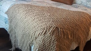 Een slaapkamer met een groot bed, een houten vloer en een schilderij van een boom aan de muur.