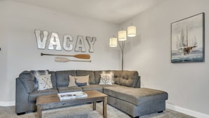 A modern living room with a gray sectional sofa, a wooden coffee table, and a wall-mounted lamp.