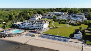 A large resort with multiple buildings, a swimming pool, and a beach area.