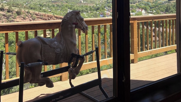 A wooden deck with a stationary horse sculpture.