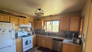 A kitchen with wooden cabinets, a stove, a dishwasher, and a refrigerator.