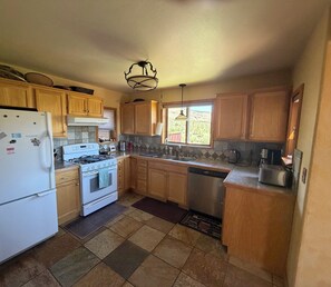 Una cocina con armarios de madera, estufa, lavavajillas y refrigerador.