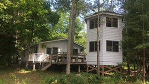 A cabin with a deck and a separate tower-like structure.