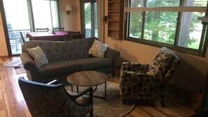A living room with a sofa, armchair, coffee table, and a dining area with a table and chairs.