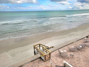 Ein Strand mit einer Holzterrasse und Liegestühlen.