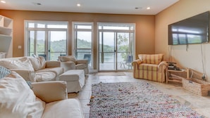 A spacious living room with a large sofa set, a patterned rug, and a flat-screen TV mounted on the wall. - Waterfront, 2025 Tram, 2023 Dock, Sleeps 14, 3BR, 3.5 Bath, Wifi @ House & Dock (Jacksboro)