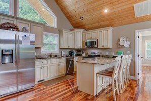Enjoy cooking in this kitchen with a central island, bar stools, and stainless steel appliances.