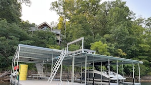 A dock with a covered area, a boat, and a house in the background. - Waterfront, 2025 Tram, 2023 Dock, Sleeps 14, 3BR, 3.5 Bath, Wifi @ House & Dock (Jacksboro)