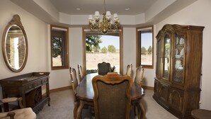 A dining room with a large wooden table, six chairs, a chandelier, a large mirror, and a cabinet.