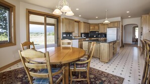 A spacious kitchen with wooden cabinets, a central island, and a dining area with a round table and chairs.