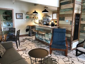 Relax in a stylish space with a mix of contemporary and natural elements, featuring a seating area, bar, and wooden panelled walls.