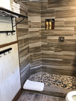 Ein Badezimmer mit Duschbereich, Handtuchhalter und Seifenspender.