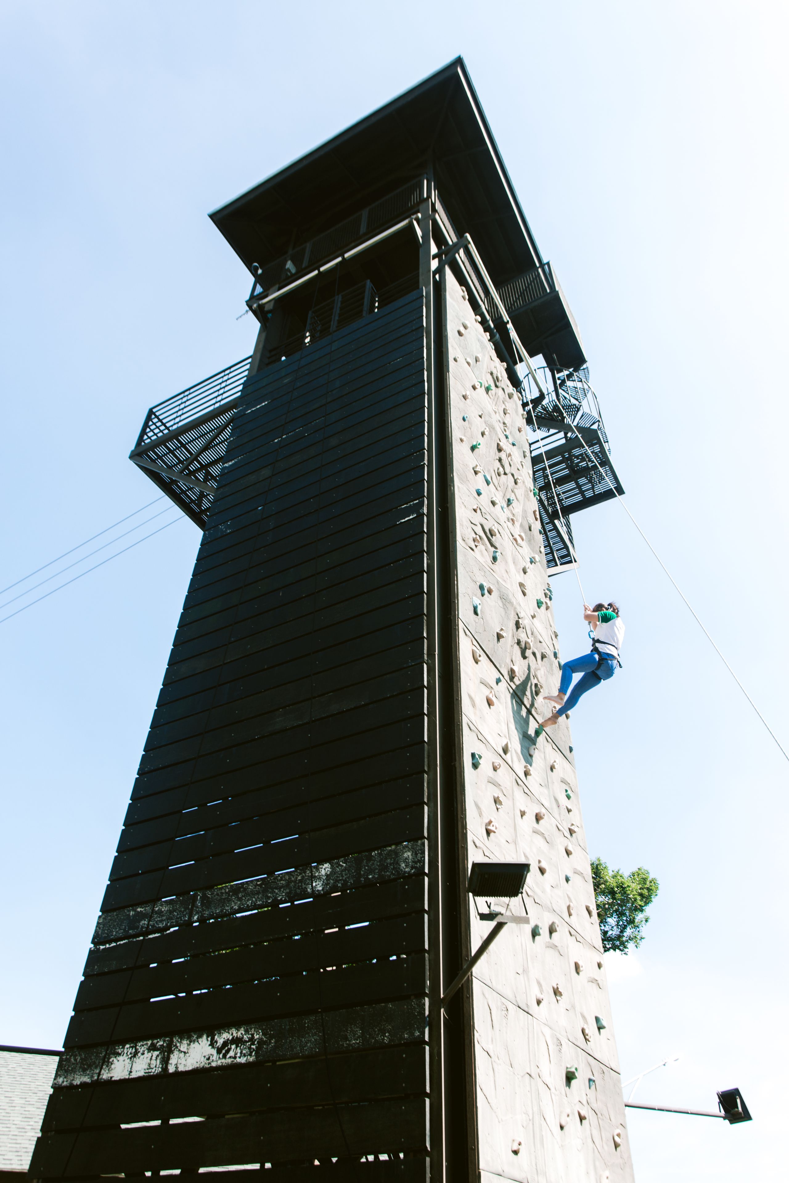 A tall climbing wall with a person climbing.