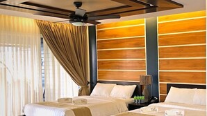Une chambre d’hôtel avec deux lits, un ventilateur de plafond, un mur décoratif en bois et un sol à motifs.