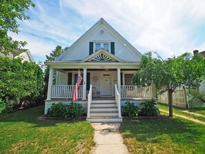 Traditional two-story house with a central entrance, porch, and well-manicured lawns.