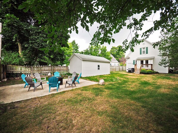 A backyard with a patio area, outdoor seating, a shed, and a house.