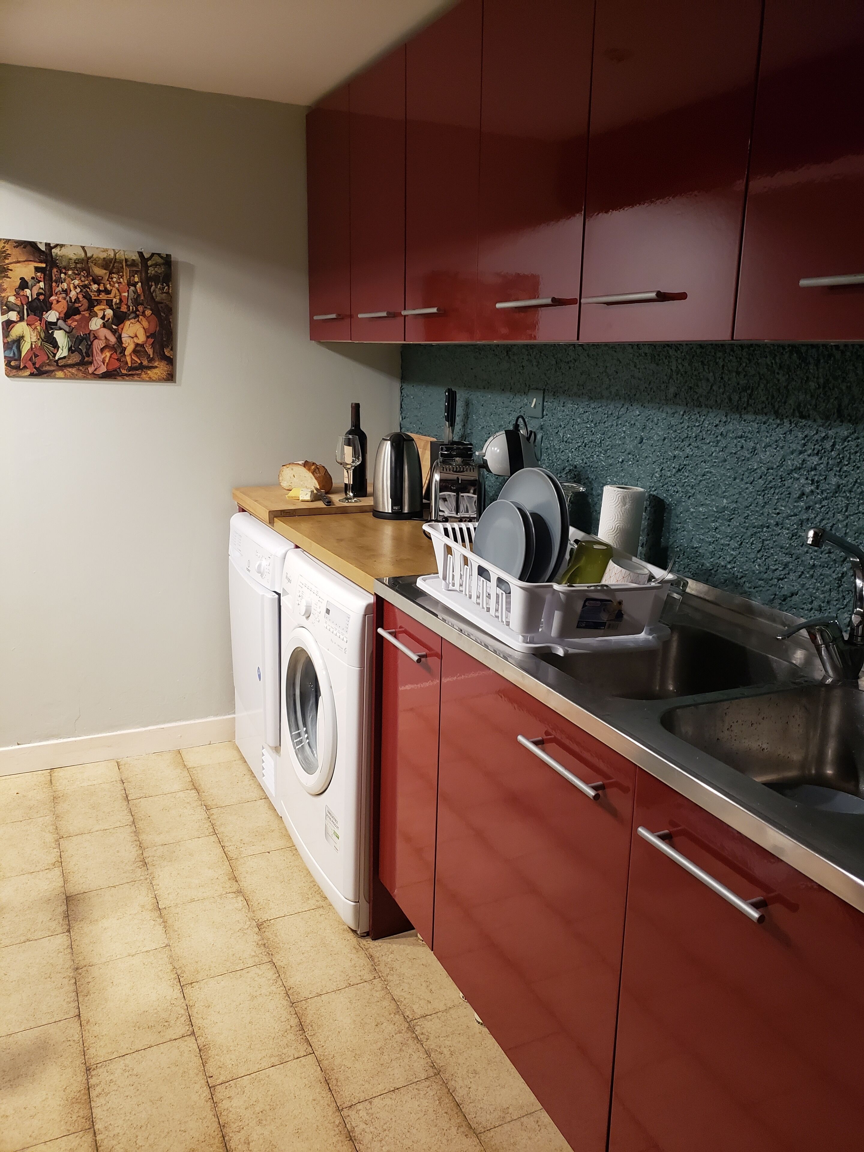 A compact kitchen with a washing machine, a sink, and a countertop with various appliances.